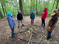 Eine Gruppe beim Waldbaden rund um ein Mandala aus Naturmaterialien